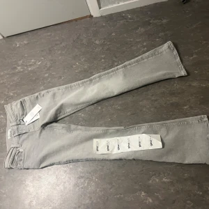 Ultra low bootcut jeans från Gina Tricot - Snygga grå jeans från Gina Tricot med bootcut passform och klassisk femficksdesign. Jeansen har en ljusgrå ton och är tillverkade i mjukt denimtyg som sitter bekvämt över höfterna och låren innan de blir vidare nedtill. Perfekt för dig som gillar retrovibbar.