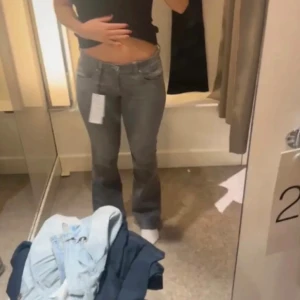 Grå bootcut jeans  - Snygga grå jeans med bootcut passform och låg midja. Jeansen har klassisk femficksdesign, dragkedja och knapp framtill. Tillverkade i mjukt jeanstyg som sitter skönt och ger en clean look. Perfekta för dig som gillar en tidlös men trendig stil.