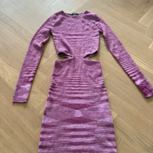 Rosa stickad cut out klänning FBSister - Säljer en rosa stickad klänning från FBSister i storlek XS. Klänningen har lång ärm, coola cut out-detaljer vid midjan och ett randigt mönster i olika nyanser av rosa och lila. Materialet är mjukt och stretchigt, perfekt för dig som gillar att sticka ut.
