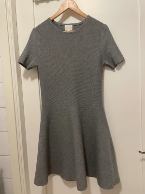 Grå ribbad kortklänning med utställd kjol - Supersnygg röd klänning med utställd kjol och rund halsringning. Modellen är kort Materialet är ribbat och stretchigt, vilket gör den bekväm och lätt att bära. Mindre i storleken. Finns även i röd. 