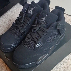 Nike Air Jordan 4 Black Cat - Säljer ett par Nike Air Jordan 4 Retro Black Cat sneakers i helsvart mocka och syntet. Klassisk siluett med meshpaneler, snörning och ikoniska Jumpman-loggor på plös och häl. Riktigt clean och tidlös look som passar till allt. Kontakta ifall du vill ha detta ikoniska paret hos dig!!