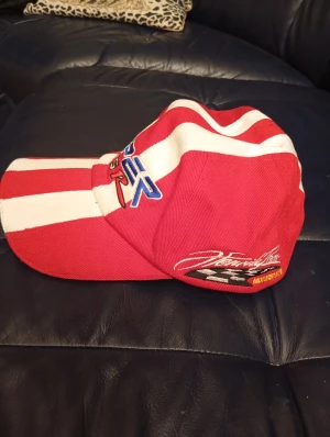 Rödvit Viper GTS-R keps - Snygg keps med breda röda och vita ränder, broderad Viper GTS-R logga i blått, svart och rött framtill samt Optima Batteries patch på sidan. Kepsen har klassisk böjd skärm och är tillverkad i bomull. Perfekt för dig som gillar racing och coola accessoarer.