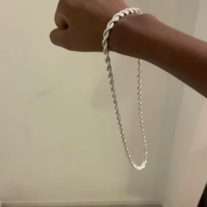 Silverfärgat tvinnat halsband - Snyggt halsband i silverfärg med tvinnad kedja som ger en cool och modern look. Perfekt för dig som gillar stilrena accessoarer med lite edge. Längden är klassisk och passar till de flesta outfits. Kedjan har ett smidigt lås och känns lätt runt halsen.
