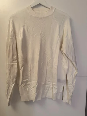 Vit stickad tröja med rund hals - Säljer en enkel och stilren vit finstickad tröja med rund hals och långa ärmar. Tröjan har ribbade muddar vid halsen, ärmslut och nederkant. Perfekt att matcha med jeans eller kjol för en clean look. Har inte använt på länge förvandlar är den lite skrynklig ☺️ 