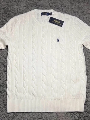 Vit kabelstickad tröja Polo Ralph Lauren - Kabelstickad vit tröja från Polo Ralph Lauren med klassisk blå logga broderad på bröstet. Tröjan e från Asien drf står det Large  på storleken men i Europa e det en medium. ett till ett, fraktar snabbt 