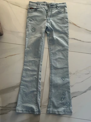 Lågmidjade bootcut jeans med fjärilsbroderi - Snygga ljusblå bootcut jeans från Newline med broderade fjärilar och små pärldetaljer på benen. Klassisk femficksmodell med normal passform och låg midja. Materialet är mjukt jeans och färgen är ljusblå, perfekt för dig som gillar unika detaljer.