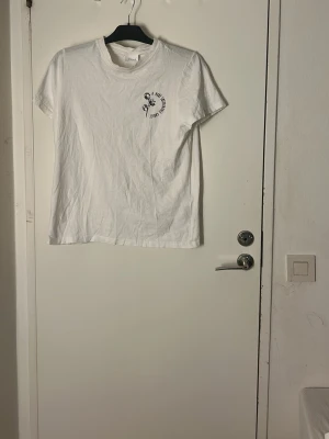 Vit t-shirt från VILA med tryck - Pris kan diskuteras  Tvätt innan leverans 💗Säljer en vit t-shirt från VILA i storlek M. T-shirten har ett litet tryck på vänster bröst och klassisk rund hals. Modellen är kortärmad och gjord i mjuk bomull, perfekt för en chill och enkel stil.