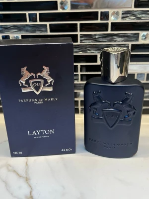 Layton Eau de Parfum 125ml - Upptäck Layton från Parfums de Marly – en exklusiv Eau de Parfum på 125 ml, tillverkad i Frankrike. Flaskan utstrålar lyx och modernitet, perfekt för dig som vill sticka ut med stil. Parfymen levereras i originalförpackning och är en ikonisk doft för unga trendmedvetna.