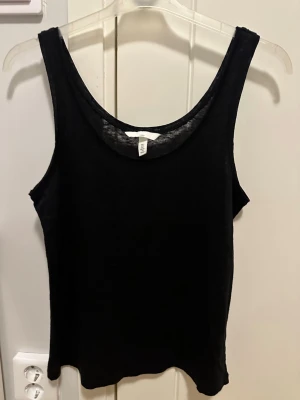 Svart linnetopp från H&M stl S  - Svart linnetopp från H&M i 100% linne. Modellen är ärmlös med rundad halsringning och har en enkel, stilren design. Perfekt för varma dagar och enkel att matcha med olika outfits. Sval och lätt känsla tack vare materialet. Aldrig använd dock tvättad en gång :) 