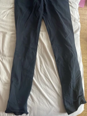 Svarta raka byxor i bomull - Säljer ett par svarta byxor med rak passform, tillverkade i mjukt bomullsmaterial. Byxorna har klassisk design utan synliga detaljer och passar dig som gillar enkel och stilren look. Perfekta att matcha med sneakers eller boots.