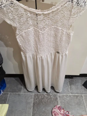 Vit spetsklänning från Chiara Forthi - Supersöt vit klänning från Chiara Forthi med spets upptill och blommigt mönster i spetsen. Kjolen är enkel och faller snyggt. Perfekt för dig som gillar romantisk stil och vill ha något ljust och fräscht. Storlek L.