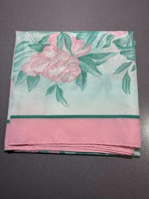 Blommig rosa och grön scarf - Scarf med blommigt mönster i ljusrosa och grönt. Scarfen har en mjuk känsla och är tillverkad i ett tunt material som liknar satin. Blommorna och bladen ger en fräsch vibe och kanten är markerad med rosa och gröna linjer. Perfekt att ha över tröjan eller på väskan som en fin detalj! Mått: ca 60x60cm. Mycket bra skick, som ny! Säljs på flera sidor, först till kvarn. 