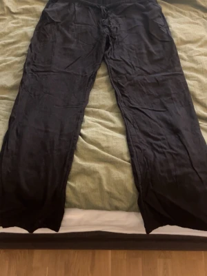 Svarta linnebyxor med snörning - Säljer ett par svarta linnebyxor med avslappnad passform och elastisk midja med snörning. Byxorna har raka ben och praktiska sidofickor. Perfekta för chill dagar eller när du vill ha något luftigt och bekvämt.