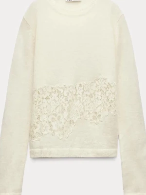 Vit stickad tröja med spets från Zara - Supersöt vit stickad tröja från Zara med lång ärm och ett brett band av blommig spets över magen. Tröjan har rund hals och mjuk, lätt transparent känsla. Perfekt att styla med jeans för en chill och trendig look.