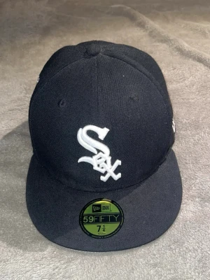 New era Kepa - Bilderna visar en svart New Era 59FIFTY keps med Chicago White Sox-logga, broderad text och gröna detaljer. Ingen väst syns på bilderna.