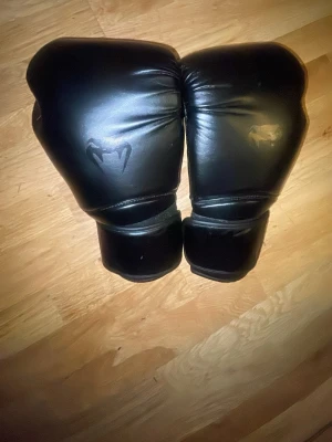 Venum boxningshandskar - Säljer ett par venum boxningshandskar i snygg och stilren design. Handskarna är tillverkade i skinn och har en klassisk form med bred kardborrestängning runt handleden för extra stöd. Perfekta för träning eller sparring på gymmet. Använda ett par ggr