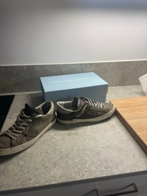 Philippe Model grå sneakers i skinn - Säljer ett par snygga Philippe Model sneakers i grått skinn med vita snören och vit sula. Klassisk låg modell med rund tå och diskreta detaljer på sidan. Kommer med originalkartong. Perfekta för dig som gillar stilrena och exklusiva sneakers. Storleken är 41 men passar mig som har 42 