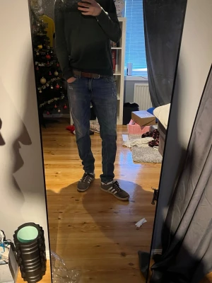 Strömberg - Säljer ett par blå jeans med snygga slitningar och tvättade detaljer. Jeansen har klassisk femficksdesign, normal passform och raka ben. Materialet är jeans och färgen är en mellanmörk blå med ljusare partier. Perfekt för dig som gillar en avslappnad stil.