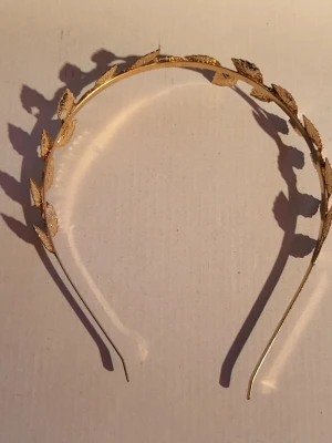 Golden leaf crown - Golden coloured leaves on a headband. Beautiful with minimal signs of wear, there is however, a factory defect and some glitter on it from when I wore it. Unknown metal. 12.2cm wide 14.5cm tall  Bundle discounts: two items 10% off (automatic) three items 15% off, five items 20% off. Message me before purchasing 3+ items for discount.