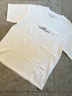 Maison Margiela vit t-shirt - Säljer en clean vit t-shirt från Maison Margiela med svart logga i storlek M. Nytt skick och fraktas inom 24h✅