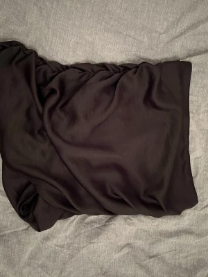 Svart omlottkjol - En svart kjol som är rak/lite dragen där fram men har en scrunch bakom. 