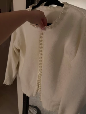 Vit kofta med pärldetaljer - Superfin vit kofta med pärlor längs halsringningen och hela knappslån framtill. Tröjan är från shein därav priset