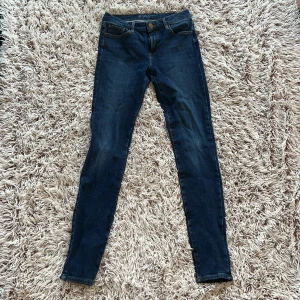 Midrise Marlie superskinny jeans blå - Snygga blå superskinny jeans från Cubus i storlek S.  Modellen har midwaist, klassisk femficksdesign och gylf med dragkedja och knapp.  Jeansen är tillverkade i stretchig denim med orangea sömmar och bälteshällor.