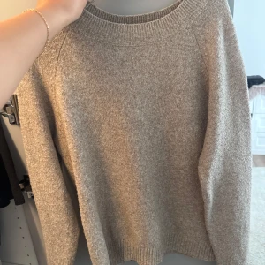 Beige stickad tröja från Vero Moda - Mysig beige stickad tröja från Vero Moda med rund halsringning och ribbade muddar. Perfekt för lager-på-lager och passar till allt. Enkel och stilren design som är lätt att matcha med jeans eller kjol.
