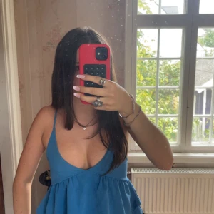 Blå topp från Fashion Nova - Supersöt unik blå topp från Fashion Nova med tunna axelband och djup v-ringning. I storlek XS. Säljer då den inte kommer till användning💕 
