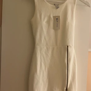 Vit formell klänning Nelly - En vit formel klänning från Nelly ONE med en slit och dragkedja därframme som går att justera. Aldri använd!