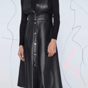 Svart lång klänning i skinnimitation Zara - Cool svart långklänning från Zara i skinnimitation med breda axelband och knappar framtill. Klänningen har en markerad midja och v-ringad överdel, perfekt att styla med en tight topp under för en edgy look.