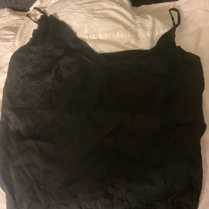 Svart omlottklänning från Gant - Supersnygg svart kortklänning från Gant med tunna axelband och omlottdesign. Klänningen har subtila broderade detaljer och är tillverkad i ett glansigt material som ger en lyxig känsla. Perfekt för dig som vill ha en stilren och elegant look.