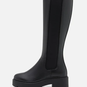 Svarta höga boots med platt sula - Snygga svarta boots med högt skaft och chunky platt sula. Fint skick!