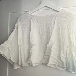 Vit blus med vida ärmar Pull&Bear - Säljer en snygg  vit blus från Pull&Bear i storlek M. Blusen har vida, flowiga ärmar och en lös passform. Den är tillverkad i ett mjukt bomullstyg och har en knappdetalj i nacken med liten öppning baktill. Perfekt för en chill och stilren look.