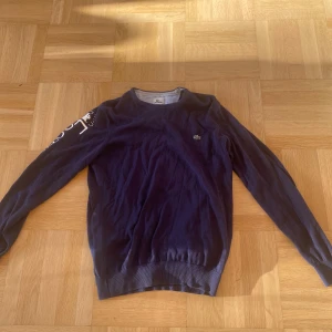 Mörkblå stickad Lacoste tröja stl s/xs - Säljer en mörkblå Lacoste sweatshirt i stl S/XS, den är använd i mycket bra skick