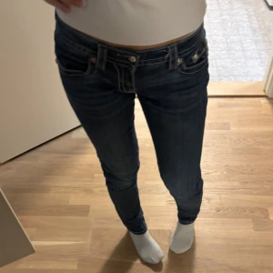 Miss Me skinny jeans med broderi - Snygga mörkblå skinny jeans från Miss Me med detaljerade broderier och paljetter på bakfickorna. Jeansen har låg midja, kontrastsömmar och coola metallknappar. Perfekta för dig som vill sticka ut med unika detaljer och en tight passform. Jag är 172 cm lång för referens