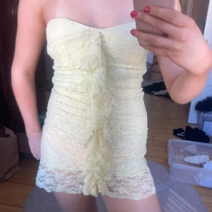 Ljusgul spetsklänning med volang - Säljer en kort, axelbandslös klänning i ljusgul spets med snygg volangdetalj framtill. Den är tyvärr lite kort för mig som är 170. 