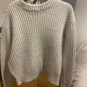 Grå stickad tröja med grov struktur - Två Mysiga stickade tröjor  med grov ribbad struktur och rund halsringning. Tröjorna har en avslappnad passform och långa ärmar, perfekt för kyliga dagar. Enkel att matcha med jeans eller kjol för en chill look. Den ena tröjan är egentligen vit men har fått en grå färg och den andra är grå.