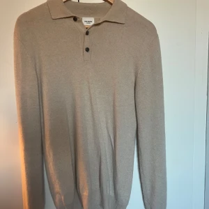 Beige kashmirpiké från John Henric - Säljer en stilren beige pikétröja i lyxig 100% kashmir från John Henric. Tröjan har klassisk krage, tre knappar framtill och långa ärmar. Perfekt för dig som gillar en clean och tidlös look med premiumkänsla. Perfekt till hösten! Nypris-1800kr/mitt pris-600kr