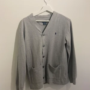 Ralph lauren cardigan  - Säljer en tvär snygg grå cardigan ifrån Ralph Lauren i 10/10 skick utan några fläckar eller liknande, den är i storleken 14-16 år som motsvarar runt 164-169, för fler frågor kom privat, som ny