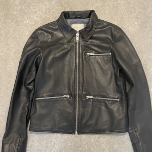 Deadwood - Skinnjacka - Snygg svart skinnjacka från Deadwood. Storlek är dam 42, jag brukar ha storlek S/M i herr. Jackan är tillverkad av 100% återvunnet fårskinn. Skriv gärna frågor eller kom med bud!