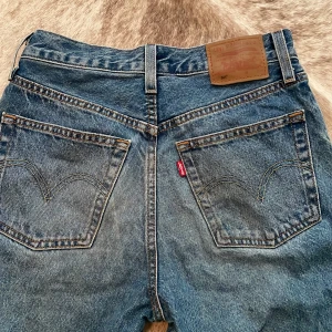 Levi's 501 Premium blå jeans - Klassiska Levi's 501 Premium jeans i blå denim med raka ben och hög midja. Snygga kontrastsömmar, femficksmodell och ikonisk läderpatch bak. Perfekta för dig som gillar tidlös stil och vill ha ett par riktigt schyssta jeans i bomull.