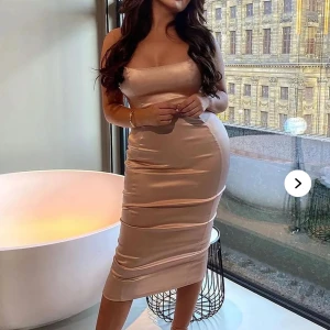 A Romantic ComedySatin Midi klänning  - Säljer en snygg och figurnära midi-klänning från Fashion Nova i champagnefärgad satin. Klänningen har smala axelband, rak urringning och slät yta som ger en lyxig känsla. Perfekt för dig som vill ha en elegant och stilren look. Helt oanvänd och ny säljs pga att jag gick upp i vikt 