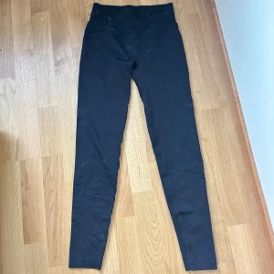 Svarta leggings från ICANIWILL - Svarta leggings från ICANIWILL med hög midja och stretchigt material. Perfekta för träning eller chill, med diskret logga framtill i midjan. Snygg och enkel design som sitter tajt och bekvämt hela dagen.