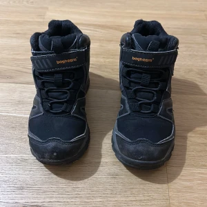 Svarta kängor från Bagheera - Svarta kängor från Bagheera med robust sula och vattentätt softshell-material. Skorna har snörning och kardborreband upptill för extra stabilitet. Perfekta för höst och vinter när du vill hålla fötterna torra och varma.