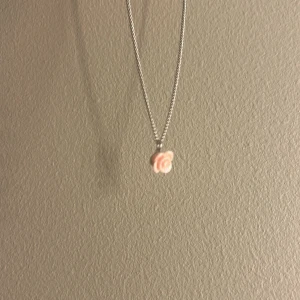 Halsband med rosa blomberlock - Sött halsband med tun silverfärgad kedja och ett litet hänge i form av en ljusrosa ros. Perfekt för dig som gillar romantiska detaljer och vill ha något unikt och gulligt runt halsen.