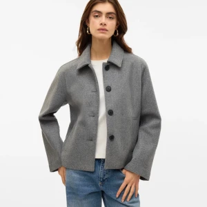 Ulljacka från Vero Moda - As snygg jacka otroligt bra material.  i grå/brun melange från Vero Moda med klassisk krage och raka ärmar. Jackan har fyra stora svarta knappar framtill och två diskreta fickor. Helt oanvänd. Dom två första bilderna är inte rätt färg på jackan men ville visa hur dom sitter på. Köpt för 699kr. Kvitto finns. 