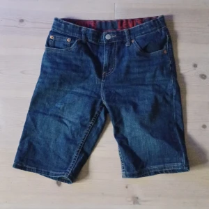Levi's 511 jeansshorts blå denim - Snygga blå jeansshorts från Levi's modell 511 med klassisk femficksdesign och knappgylf. Shortsen har en normal passform och är tillverkade i slitstark denim med tydliga sömmar och Levi's ikoniska läderpatch bak i midjan.