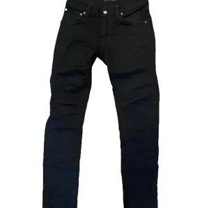 Svarta slim jeans från Nudie Jeans - Svarta jeans från Nudie Jeans med klassisk femficksdesign och smal passform. Byxorna har svarta sömmar, silverfärgade nitar och knapp, samt diskret logga på bakfickan. Tillverkade i mjuk bomull med stretch för extra komfort. Nypris 1400 mitt pris 549. Pris kan diskuteras 