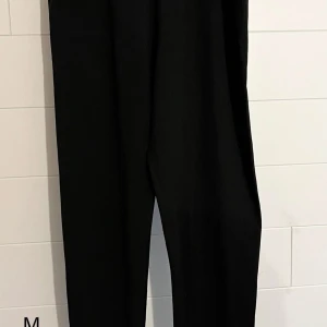 Svarta leggings i rak modell - Svarta leggings med rak passform och klassisk look. Byxorna har hög midja och är perfekta för en stilren outfit. Materialet känns mjukt och följsamt, vilket gör dem bekväma att bära hela dagen.